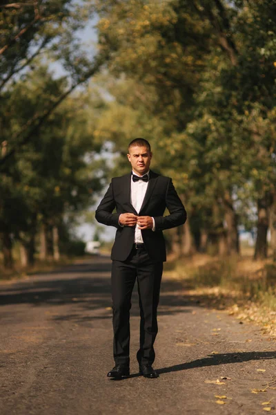 젊은 남자는 공원에서 산책. 검은 양복에 잘생긴 신랑 — 스톡 사진