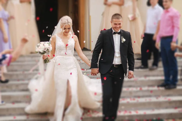 Hermosa pareja bajar las escaleras de la iglesia después de la ceremonia de boda — Foto de Stock
