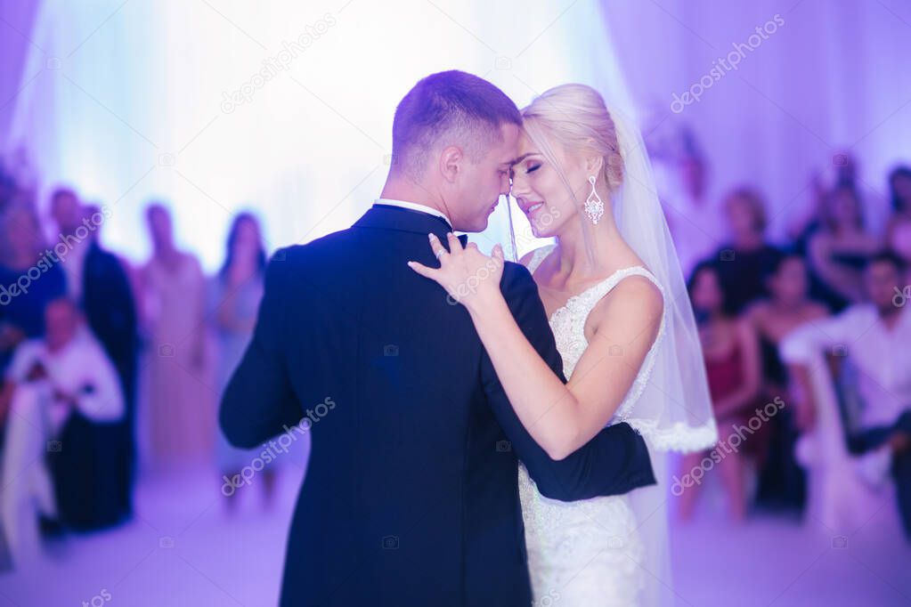 Portrait of first dance of stylish wedding couple. Handsome groom and elegant bride in the restaurant