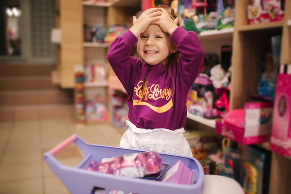 Αξιολάτρευτο κοριτσάκι που ψωνίζει παιχνίδια. Χαριτωμένη γυναίκα σε κατάστημα παιχνιδιών. Ευτυχισμένο νεαρό κορίτσι που επιλέγει παιχνίδι — Φωτογραφία Αρχείου