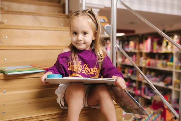 漂亮的小女孩在玩具店里看书 — 图库照片
