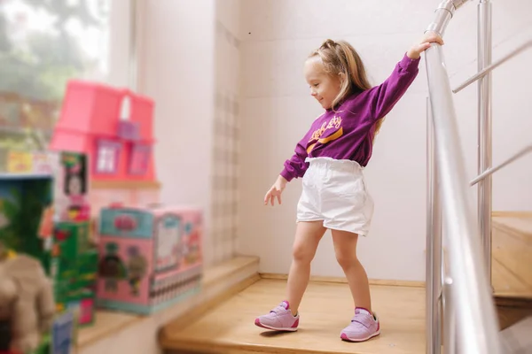 Boldog kislány sétál a játékboltban. Aranyos lány válasszon játékot. Imádnivaló nő a gyerekközpontban. — Stock Fotó