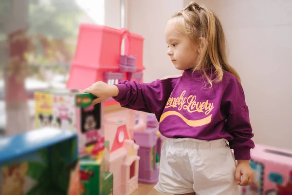 Boldog kislány sétál a játékboltban. Aranyos lány válasszon játékot. Imádnivaló nő a gyerekközpontban. — Stock Fotó