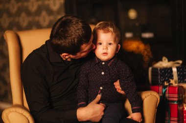 Evdeki koltukta oturan oğlu olan yakışıklı bir adam. Noel havası