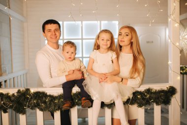 Mutlu aile Noel 'de birlikte vakit geçirir. Anne, baba, kız ve oğlanın kış tatilindeki portresi.