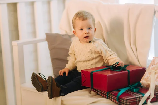 Kleine jongen die buiten op de bank zit in de kersttijd. Gelukkig kind — Stockfoto