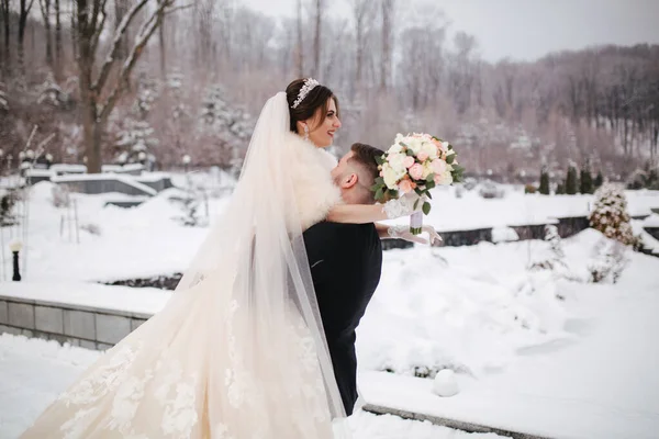 Os recém-casados no parque das bruxas andam por aí. Bonito noivo e bela noiva cercada de neve. Casamento de inverno — Fotografia de Stock
