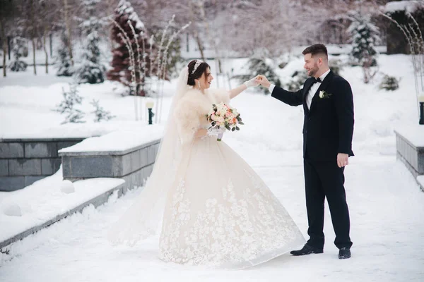 外を歩く冬の時間に結婚式のカップル。美しい花嫁とハンサムなひげそりの新郎 — ストック写真