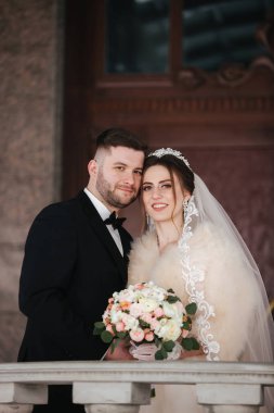 Damadın genç gelini balkonda duruyor. Kışın kürk mantolu gelin