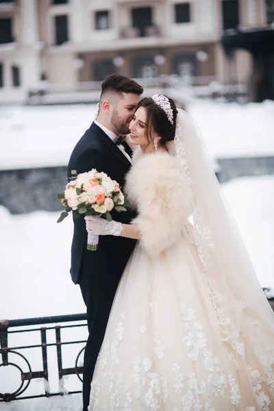 Wedding couple in winter time walking outside. Beautiful bride and handsome bearded groom