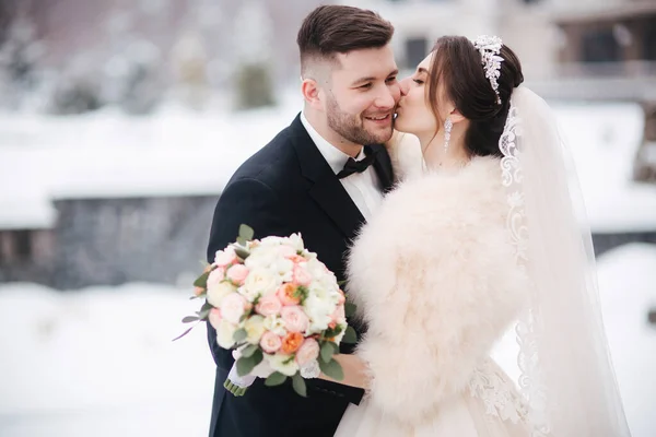 Matrimonio coppia in inverno a piedi fuori. Bello sposo barbuto bacio bella sposa — Foto Stock