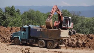 Bir kazıcı kömür kazar ve büyük bir çöp kamyonuna döker.