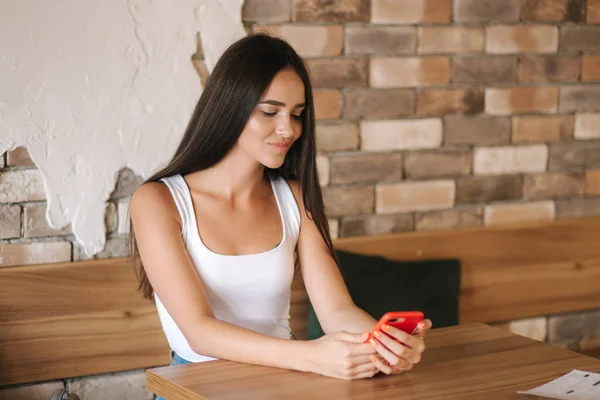Aantrekkelijke jonge vrouw die telefoon gebruikt in het café. Mooi brunette meisje dat kletst. Alleen in het café — Stockfoto