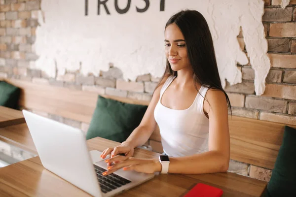 Aantrekkelijk meisje werkend op laptop in café. Mooi meisje die computer gebruikt voor het werk. Meisje dat cappuccino drinkt in een café. Olnile werk, freelancer. Een vrouw alleen in het café. Sociale afstand — Stockfoto