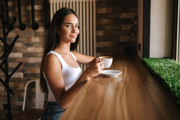 Vonzó fiatal nő telefon segítségével a kávézóban. Gyönyörű barna lány beszélgető — Stock Fotó