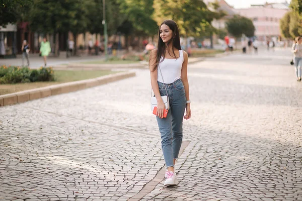 Привлекательная молодая женщина, гуляющая одна в центре города в летнее время. Женщина ходит одна. Счастливая женщина на улице. Социальное дистанцирование — стоковое фото