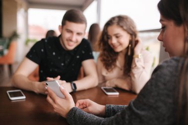 Bir grup ağaç arkadaş terasta. İnsanlar kafede buluşuyor. Kafede birlikte oturan arkadaşlar. Akıllı telefonunda bir çift için bir kadın şovu