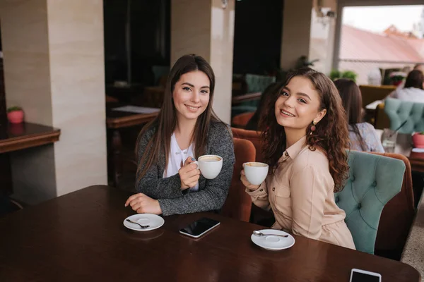 Zwei Freundinnen trinken im Restaurant Kaffee und reden. Schöne Frauen, die sich im Café treffen. Ende der Quarantäne — Stockfoto