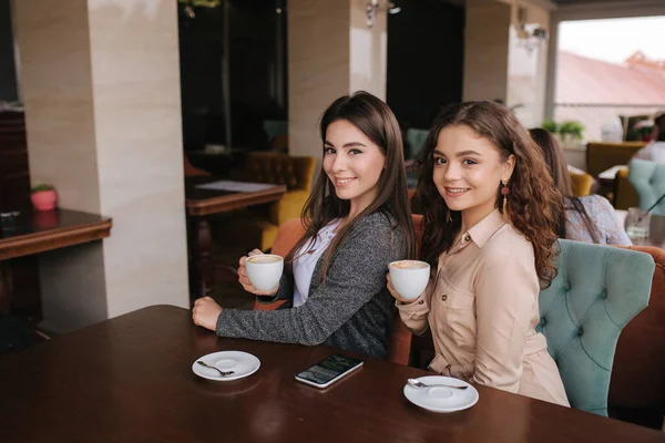 Dwie przyjaciółki piją kawę w restauratn i mówią. Piękne kobiety spotykające się w kawiarni. Koniec kwarantanny — Zdjęcie stockowe