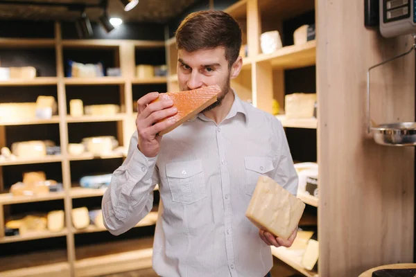 Portrait of Handsome bearded man sniff aged cheese in shop