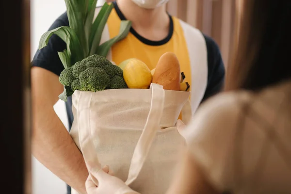 Доставка человек в маске и перчатках принести свежие продукты питания для клиентов домой. Сиди дома. Концепция покупок — стоковое фото