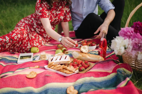 Primer plano de la mano tomar fresa en mini picnic al aire libre. Hombre y mujer comen afuera —  Fotos de Stock