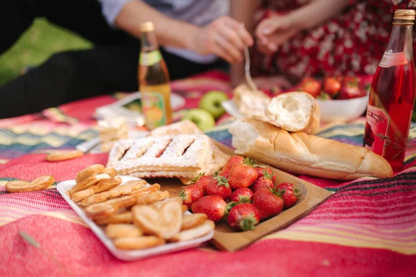 Primer plano de hombre y mujer tiene picnic no alcohólico al aire libre. Fresa, limonada, pan y otros aperitivos — Foto de Stock