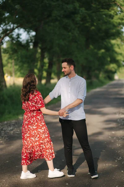 Parkta yürüyen güzel bir çift. Dışarıda dans eden yakışıklı bir adamla mutlu genç bir kadın. — Stok fotoğraf