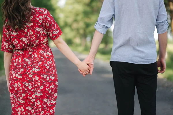 Вид сзади на красивую пару, гуляющую в парке. Счастливая молодая женщина с красивым мужчиной — стоковое фото