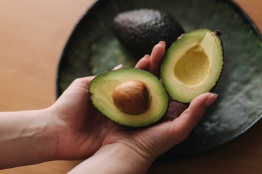 Kadınların elindeki taze kesilmiş avokadonun en üst görüntüsü. Vejetaryen gıda konsepti