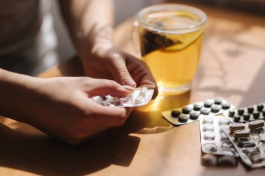 Kadın eli hapları yakın tut. Haplı el ve limonlu siyah çay. Dokunulmazlık. Vitaminler