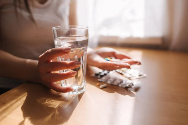 A női kezek közelről tartják a tablettákat. Kézzel pirulákkal és fekete teával citrommal. Védettség. Vitaminok — Stock Fotó