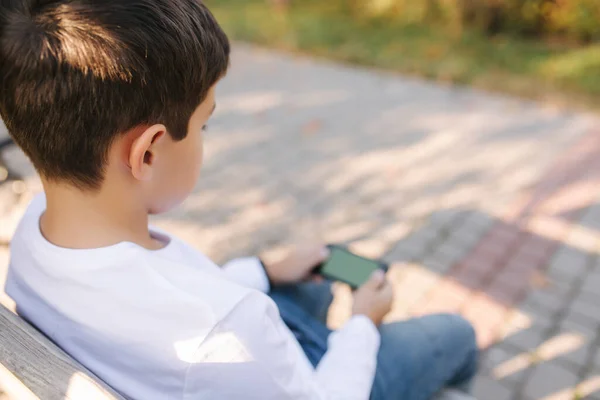 Teenage boy gioca online sul suo smartphone nel parco dopo le lezioni a scuola — Foto Stock