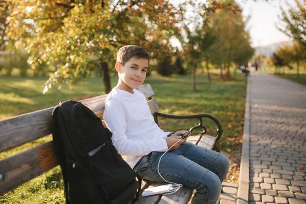 Adolescent garçon en chemise blanche utiliser powerbank pour charger son smartphone otside. Batterie faible sur smartphone — Photo