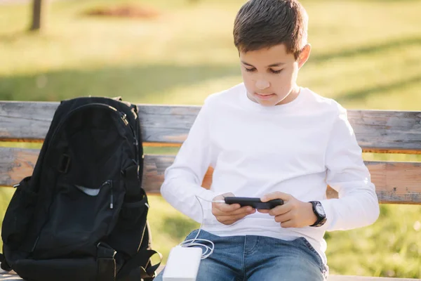 Menino adolescente de camisa branca usar powerbank para carregar seu smartphone otside. Bateria fraca no smartphone — Fotografia de Stock