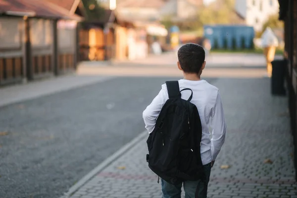 Vista posterior de niño en camisa blanca con mochila negra ir a casa después de la lección — Foto de Stock