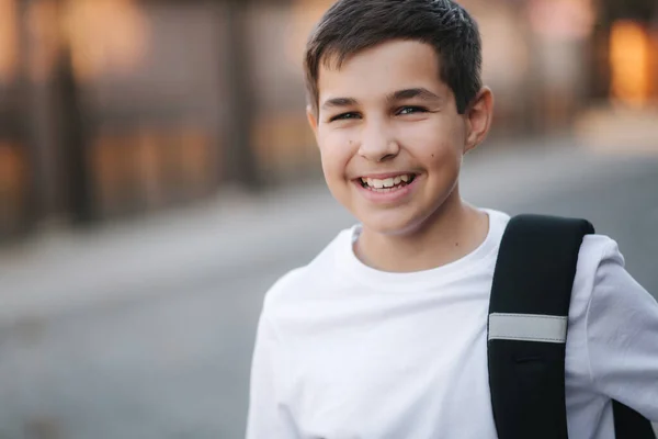 Close-up portret van gelukkig glimlachende tiener jongen in wit sweatshirt met rugzak buiten — Stockfoto