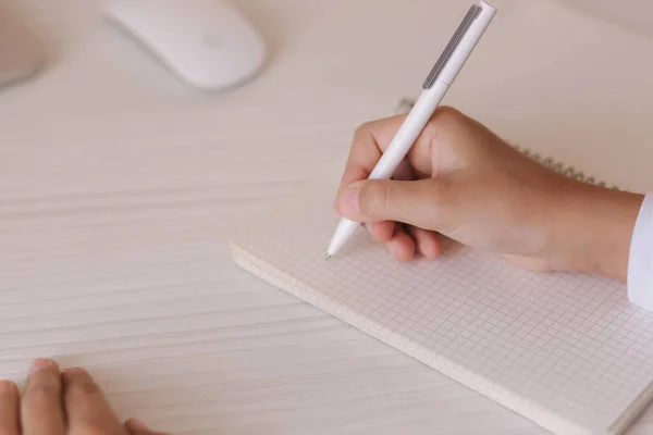 Estudiante de escuela en el escritorio de su habitación. El muchacho usa el portátil y escribe en el cuaderno. Libros y tabletas sobre la mesa. Estudiar en casa durante la cuarentena — Foto de Stock