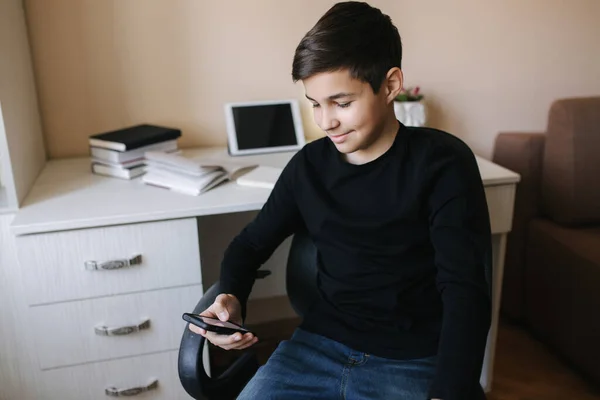 Schoolboy em casa usar smartphone durante o intervalo. Estude em casa. Sorriso jovem feliz — Fotografia de Stock