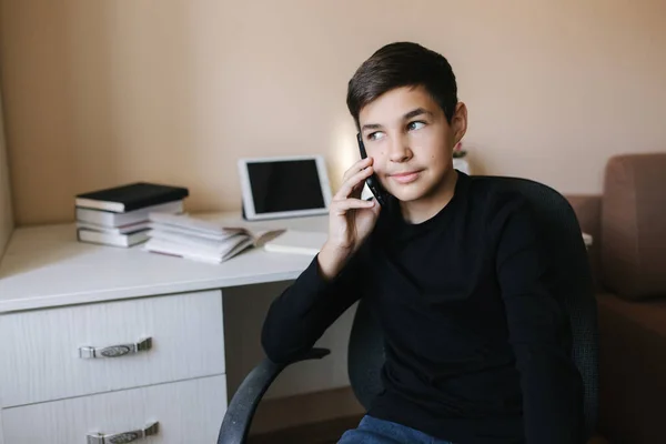 Ritratto di giovane adolescente a casa che parla per telefono. Contesto di tablet e libri — Foto Stock