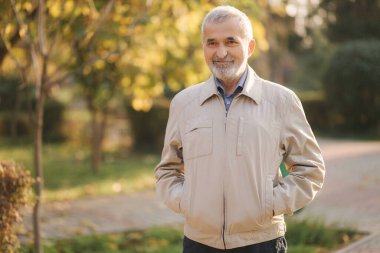 Yakışıklı sakallı yaşlı adam gözlük taktı. Parktaki gri saçlı yaşlı adam.