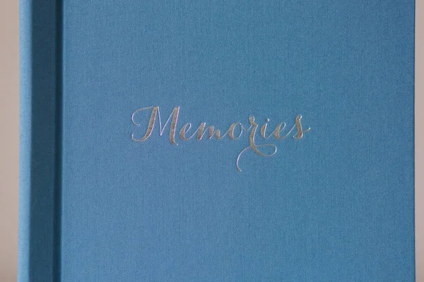 Photobook fermé sur table en bois blanc. Album de mariage textile bleu avec gaufrage argent — Photo