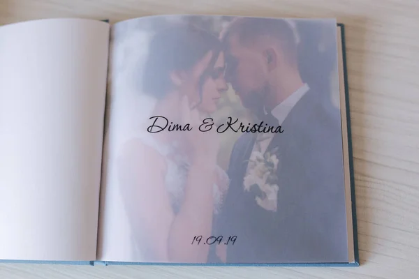 Aufgeschlagenes Fotobuch mit Durchschreibepapier mit Bräutigam und Braut auf weißem Holztisch — Stockfoto