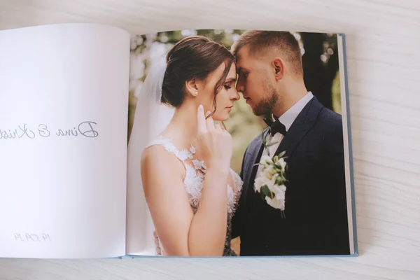 Aufgeschlagenes Fotobuch mit Foto eines schönen Paares auf weißem Holztisch — Stockfoto