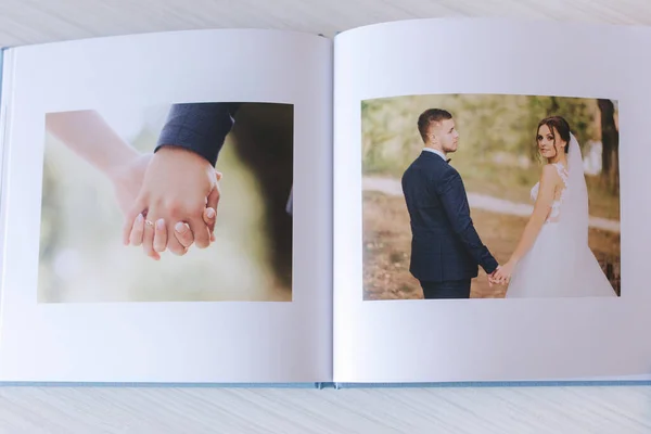 Photobook ouvert avec photo tordante de beau couple sur une table en bois blanc — Photo