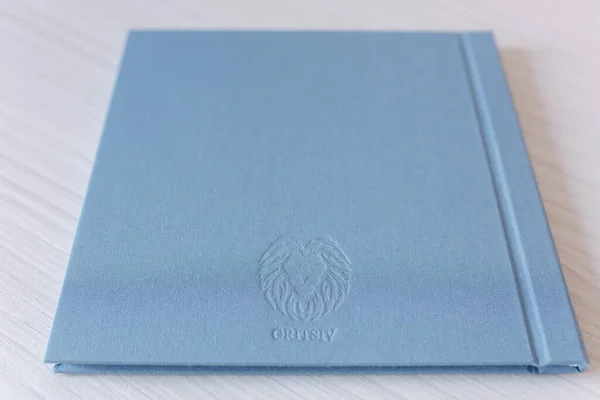 Fotolivro fechado sobre mesa de madeira branca. álbum de casamento têxtil azul com gravura de prata — Fotografia de Stock