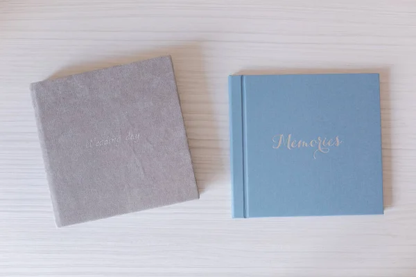 Deux photobooks fermés sur table en bois blanc. Album de mariage bleu et gris avec gaufrage argent — Photo