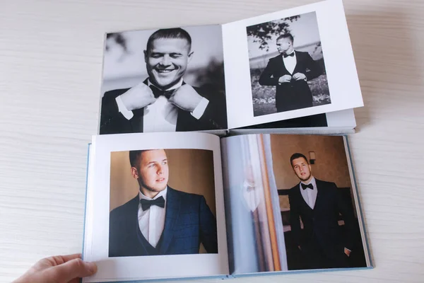 Two open photobook with groom on white wooden table. Comparison — Stock Photo, Image