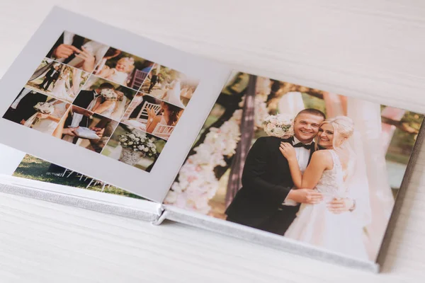 Открыть фотокнигу с закручивающейся фотографией красивой пары на белом деревянном столе — стоковое фото