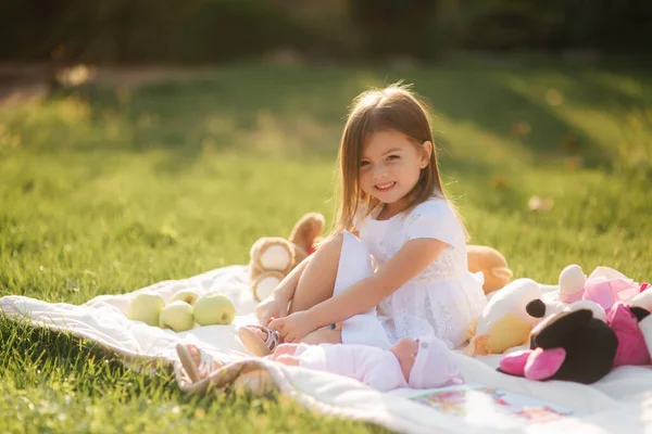 Schattig klein meisje zit buiten op de ruit en leest het boek. gelukkig glimlach baby meisje tijd doorbrengen op achtertuin in zonsondergang — Stockfoto